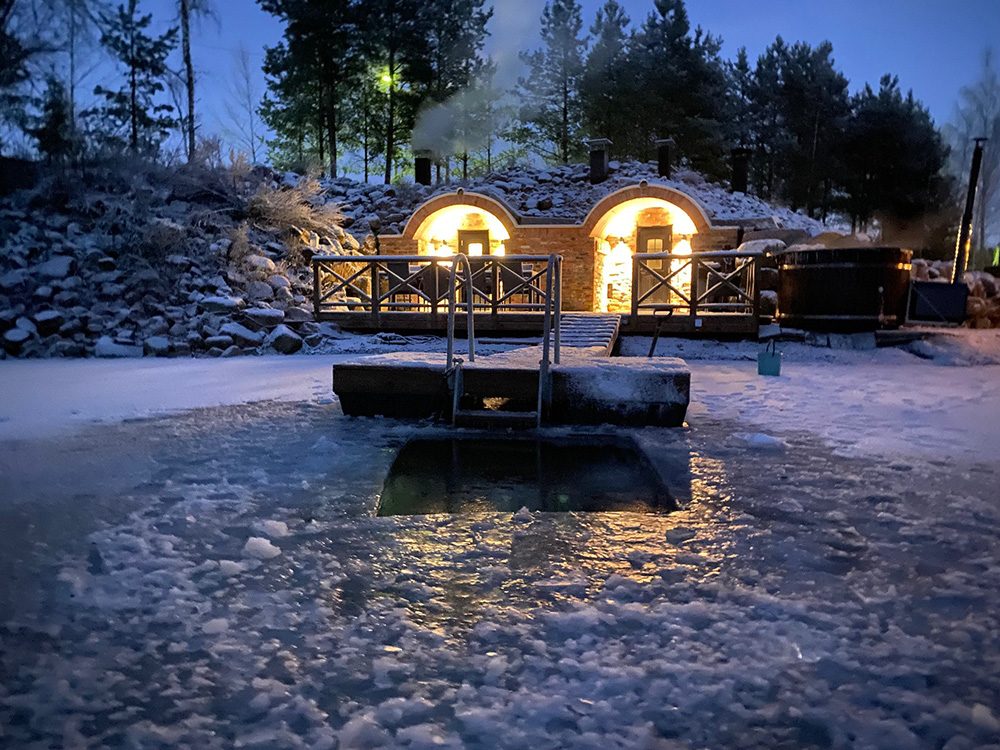 Savusauna lammen takaa nähtynä lämpimässä iltavalossa.