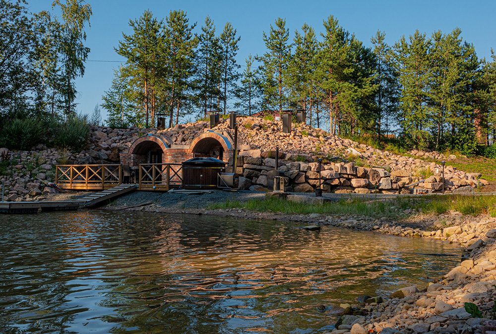 Savusauna lammen rannalla talvi-illan valaistuksessa.