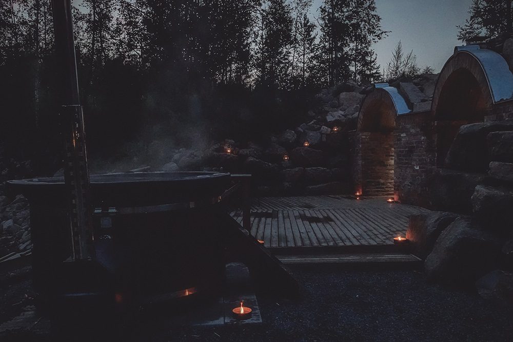 Palju höyryää savusaunan pihalla iltahämärässä.